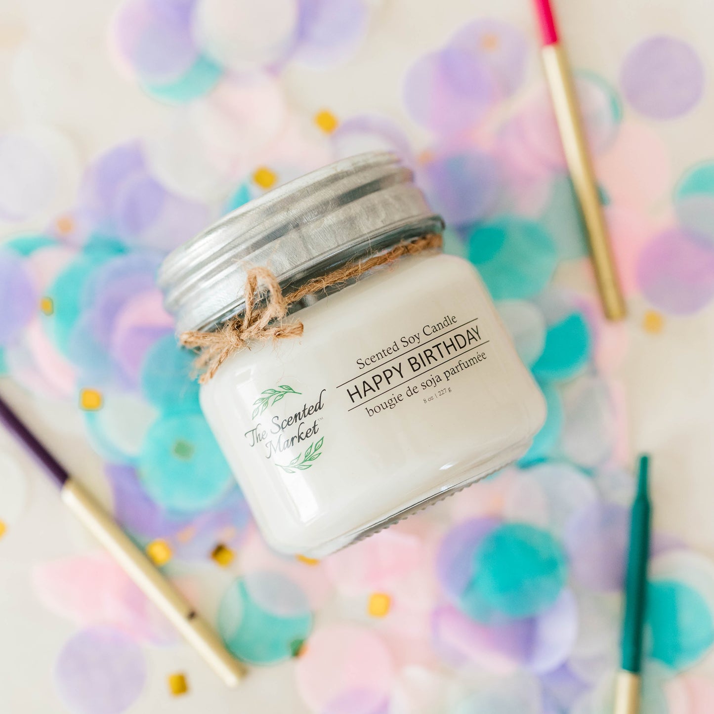 Candle labeled 'Happy Birthday' on a surface with colorful confetti